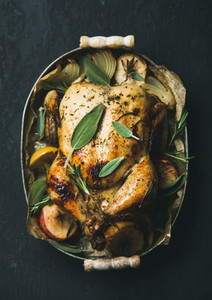 Oven roasted whole chicken with fresh sage leaves and apples