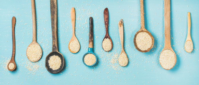 Quinoa seeds in different spoons over blue background
