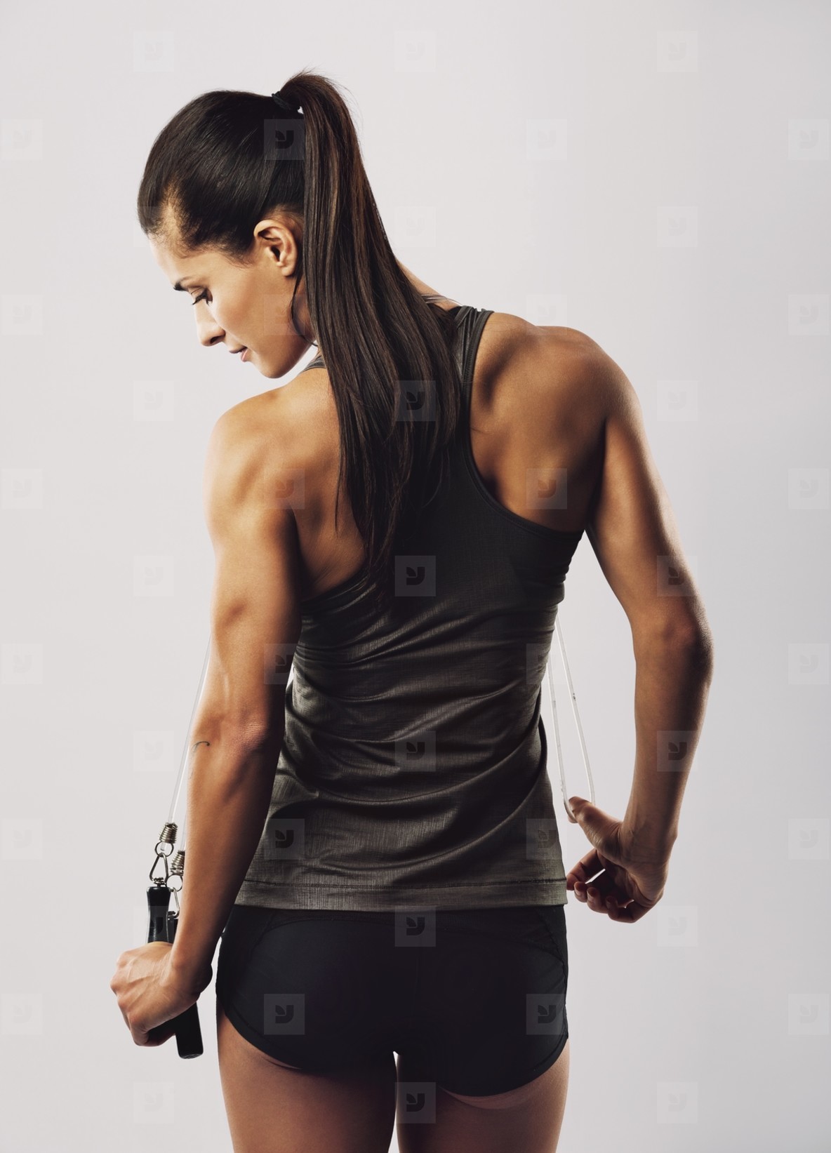 Female athlete with jumping rope posing on grey background