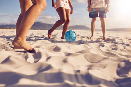 Friends playing soccer on the beach