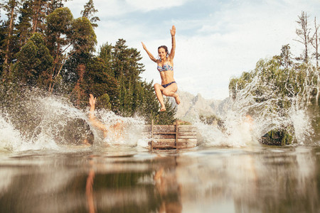 Women jumping into a lake from jetty