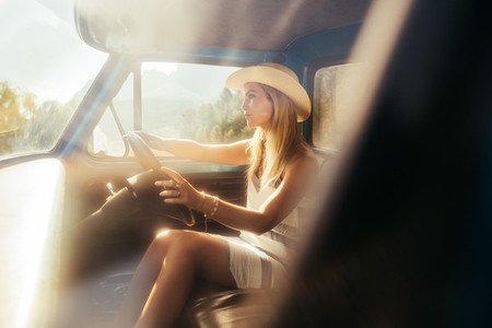Beautiful young woman driving a car on sunny day