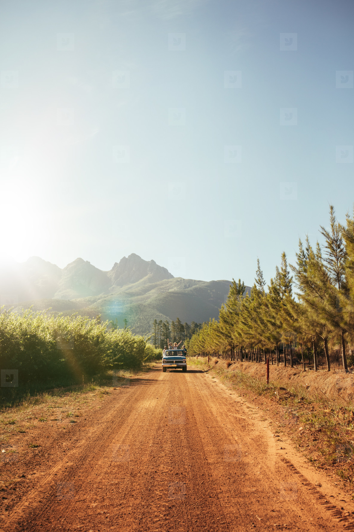 Distant car approaching on a rural dirt road on a sunny day