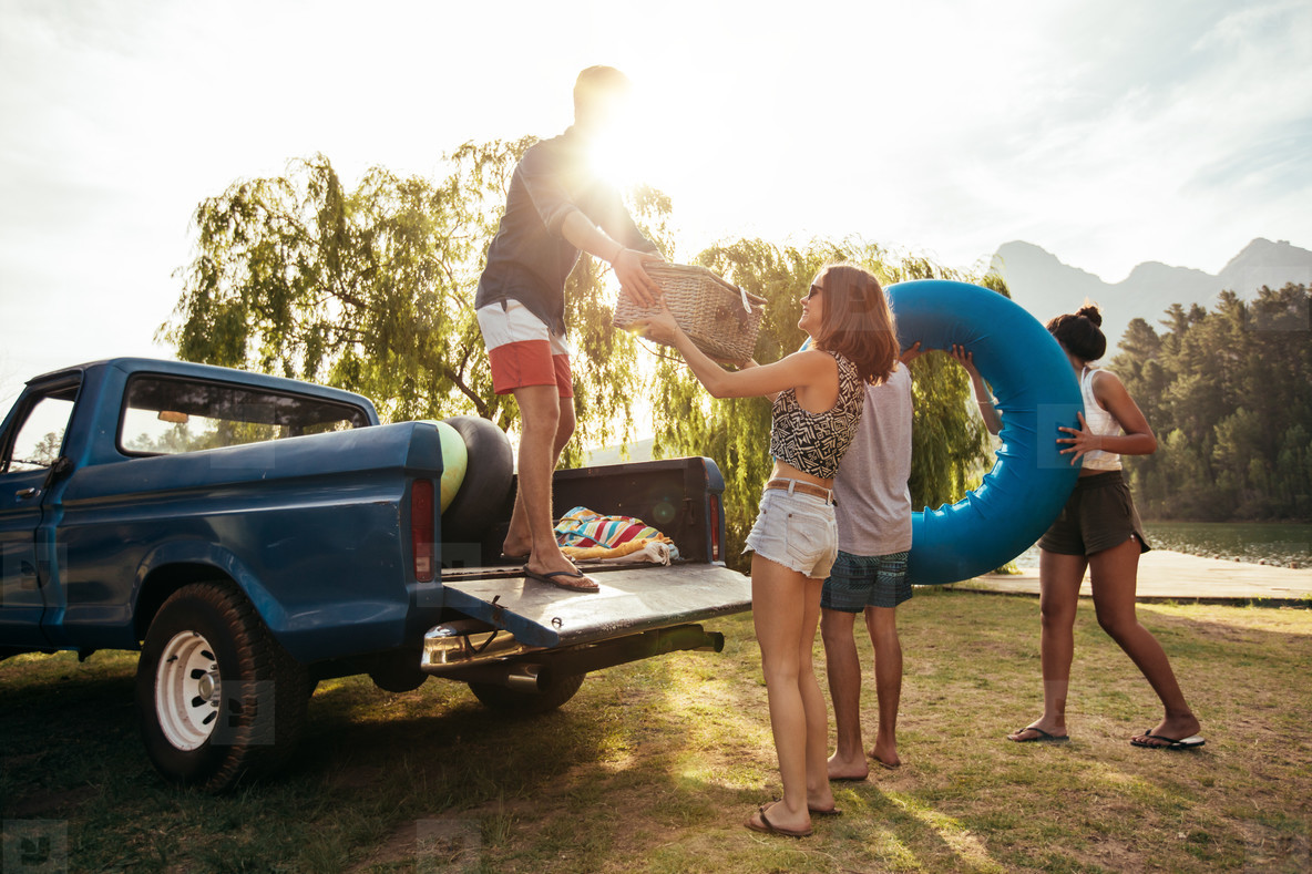 Young friends unloading pickup truck on camping trip