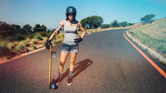 Young woman with a longboard on countryside highway