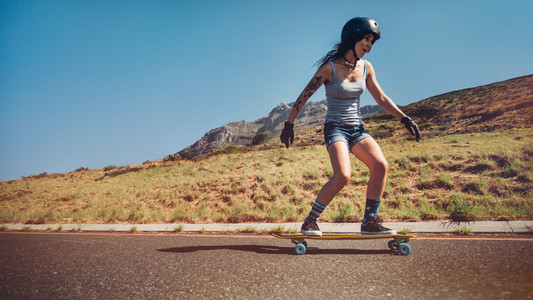 Young woman skateboarding down a road