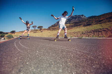 Young couple skateboarding on the road