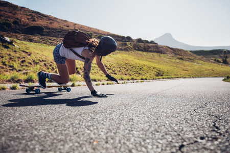 Young woman practicing skateboarding on rural roads