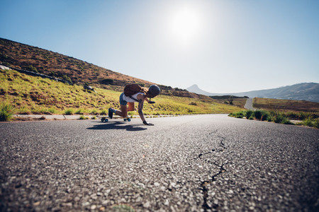 Female skater practicing skateboarding on rural roads