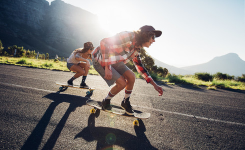 Young friends longboarding down the road