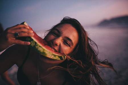 Woman eating watermelon on beach