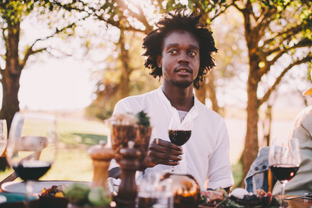 Afro American man enjoying wine at lunch party