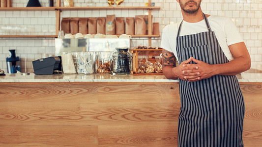 Man standing at a coffee shop counter with an apron