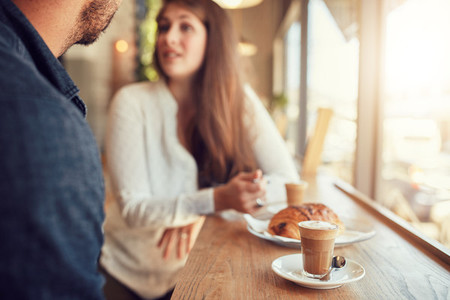 Cup of coffee and food on table with couple talking in cafe