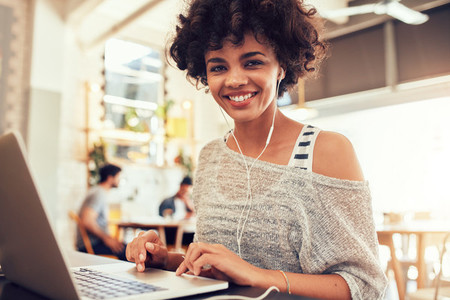 Happy young african woman  at cafe with a laptop