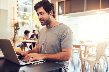 Young guy at a cafe surfing internet on laptop