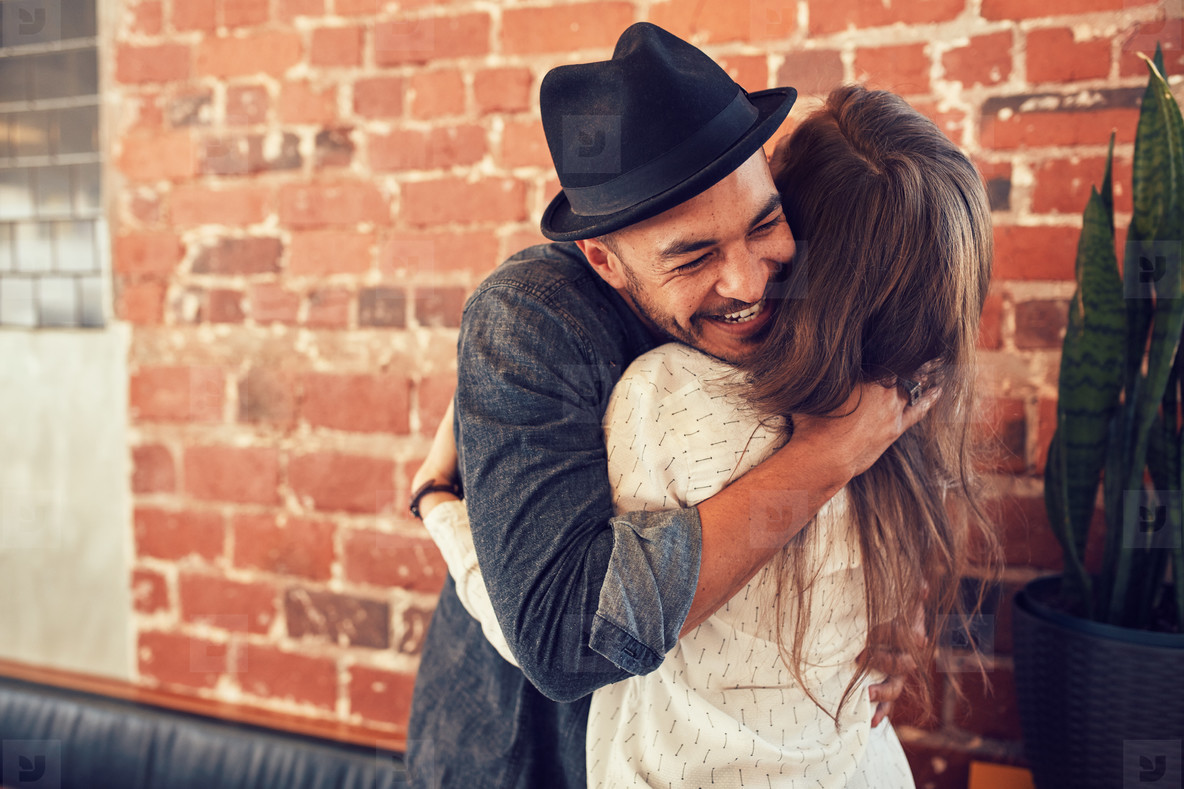 Young man hugging a woman in a coffee shop