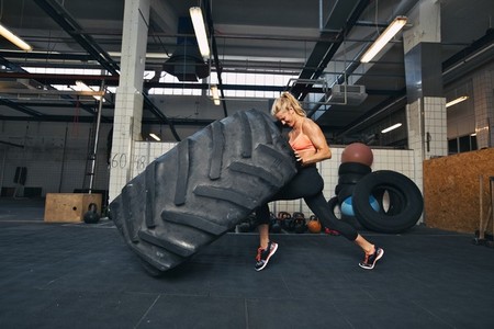Crossfit woman flipping a huge tire at gym
