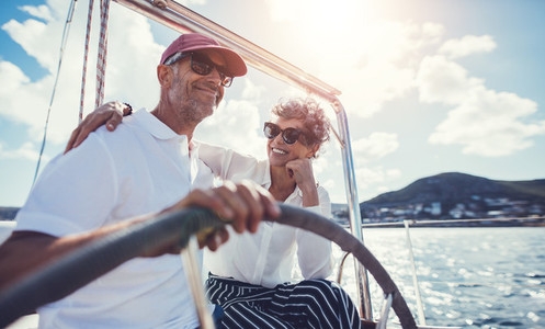 Senior couple having fun sailing at the wheel of a yacht