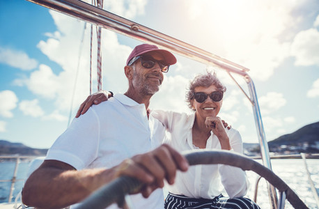 Happy mature couple at the wheel of a yacht