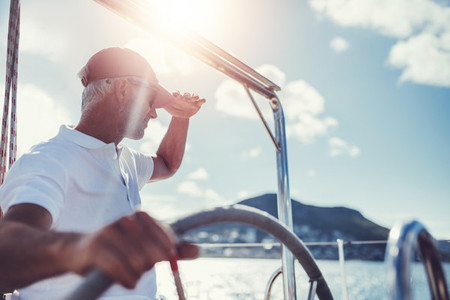 Mature man at the wheel of a yacht