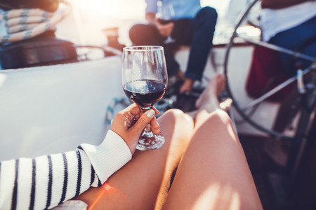 Red wine glass in hand of a woman on boat