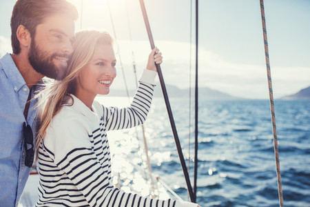 Happy young couple on sail boat looking at a view