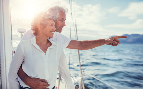 Smiling senior couple on yacht looking away