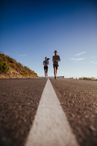 Two young people jogging on the road