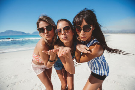 Beautiful young women blowing kisses on the beach