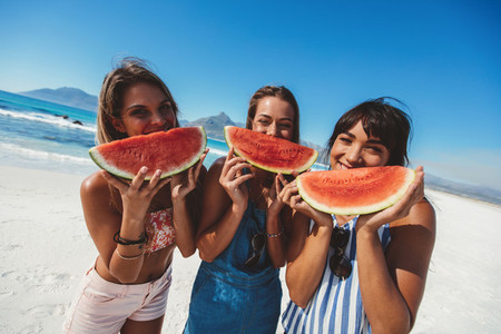 Female friends eating watermelon at the beach
