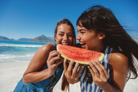 Young women enjoying watermelon on beach vacation