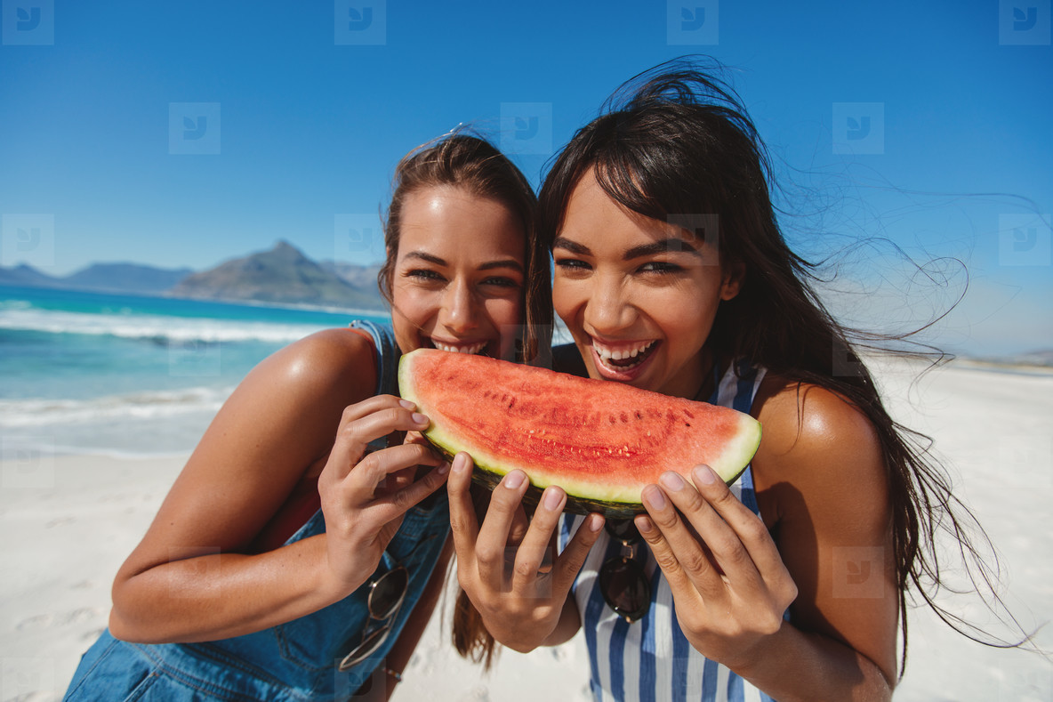 Female friends on beach having a slice of watermelon