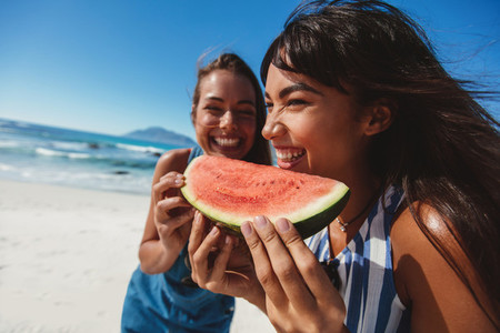 Female friends eating watermelon at the shore