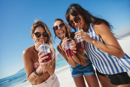 Female friends on the beach drinking ice tea