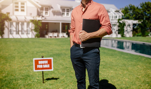 Male real estate broker outside a house for sale
