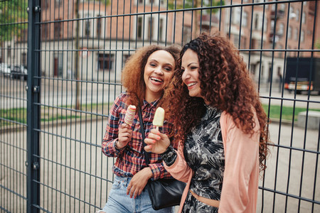Happy women eating an ice cream outdoors