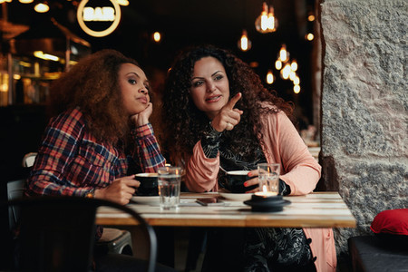 Two young women at restaurant looking away