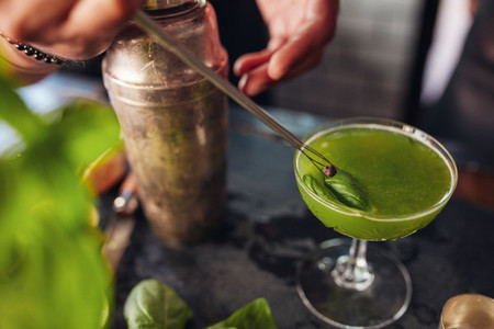 Barman hands garnishing fresh green cocktail