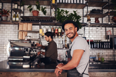Happy young male coffee shop owner standing