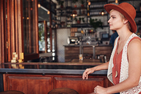 Beautiful young woman sitting alone at bar counter