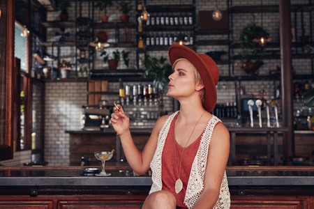 Attractive young woman smoking in a bar