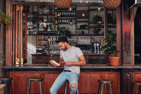 Modern young man reading a book in cafe