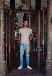 Stylish young man standing at the front door of coffee shop