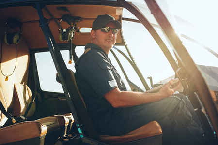 Happy male pilot in a helicopter cockpit
