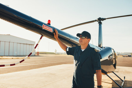 Pilot standing at the tail of a helicopter