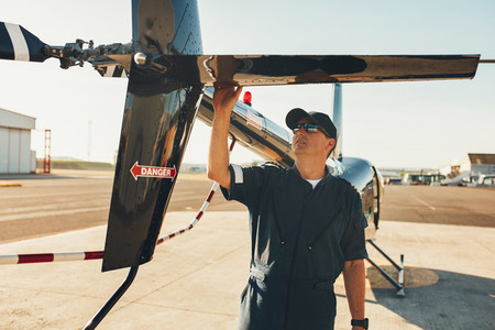 Male pilot examining helicopter tail wing