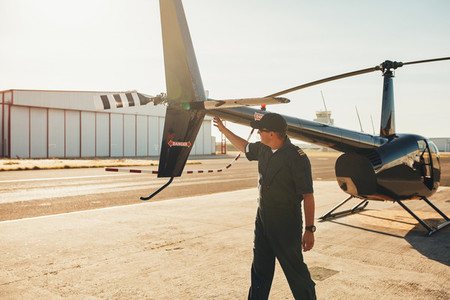 Pilot checking helicopter tail during preflight check