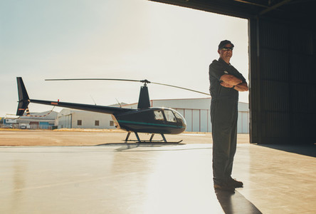 Confident pilot standing in airplane hangar