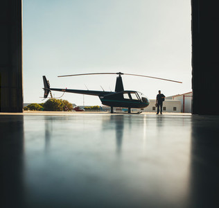 Silhouette of helicopter and a pilot in hangar